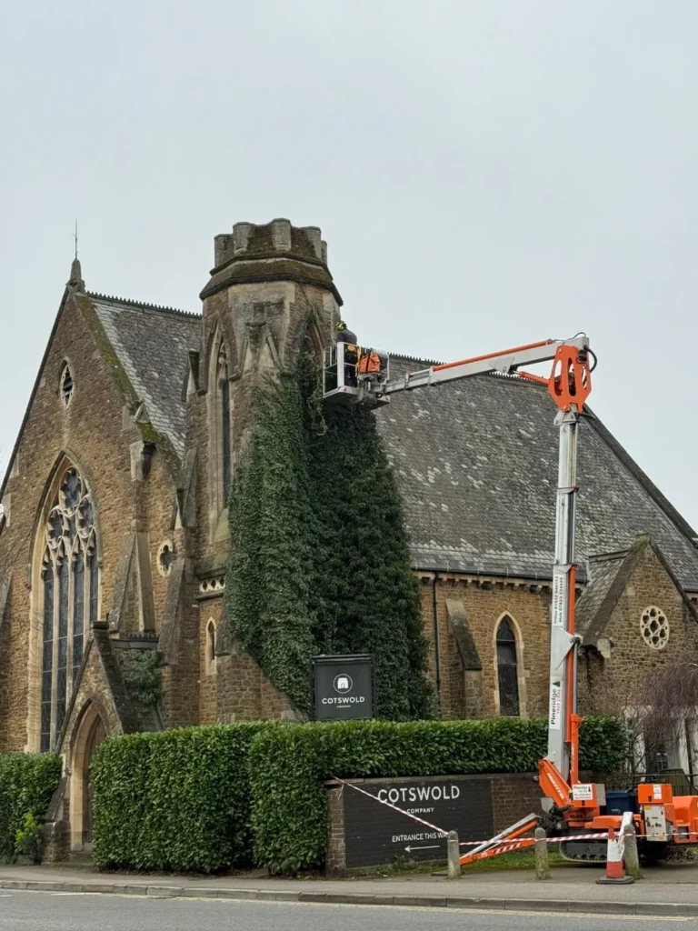 Cherry picker cutting back ivy on a church